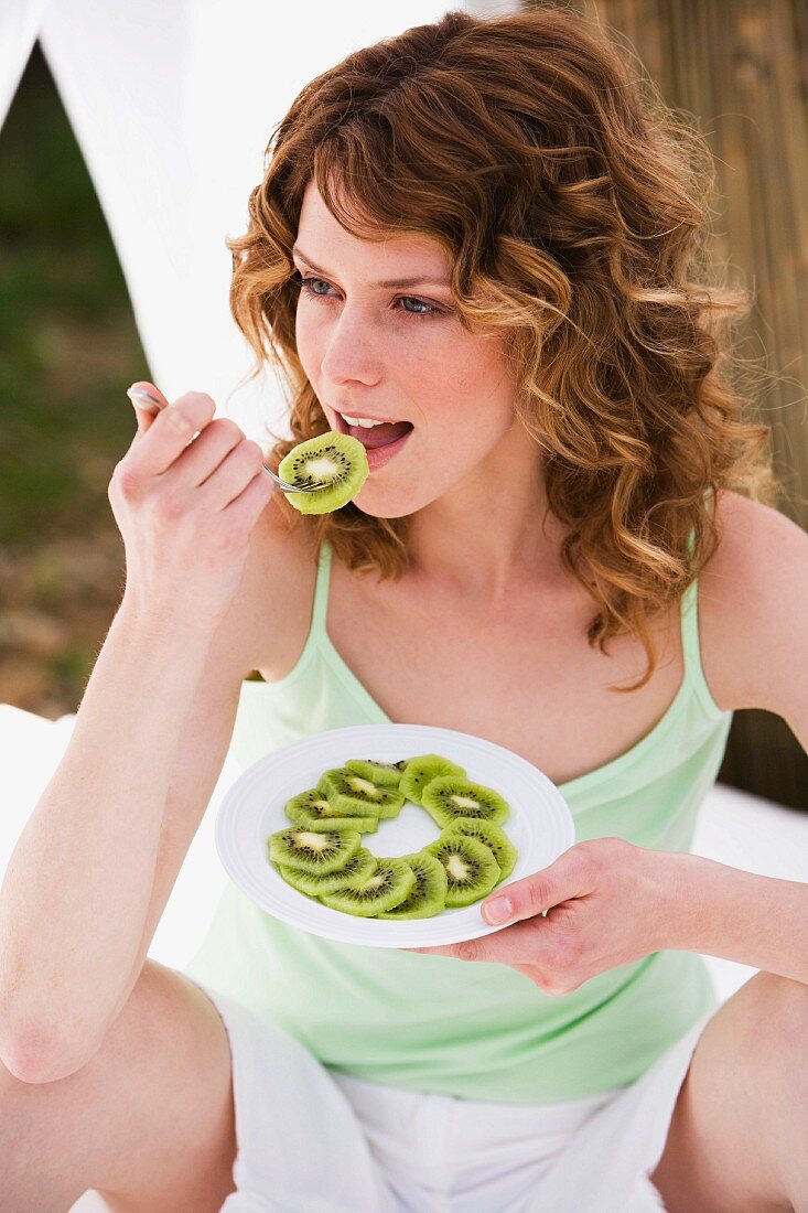 Woman eating kiwi fruit