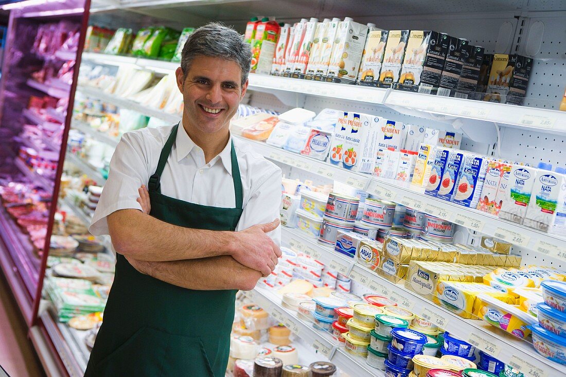 Shop assistant in front of chiller cabinets of dairy products