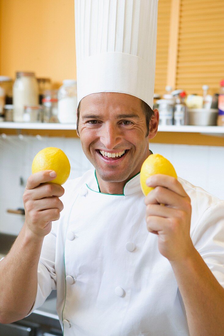 A chef holding up two lemons