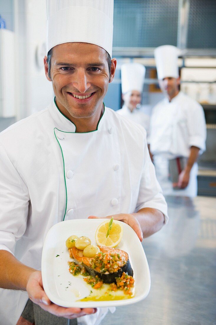 A chef with a piece of salmon fillet arranged on a plate