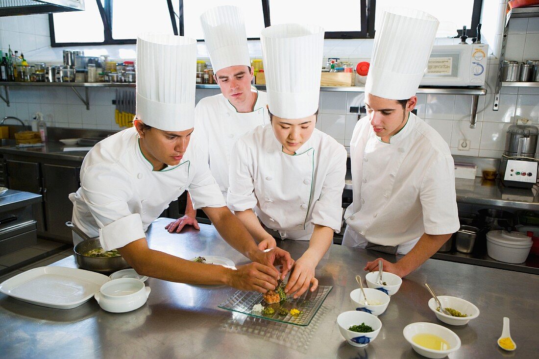 Chefs in a commercial kitchen preparing a dish