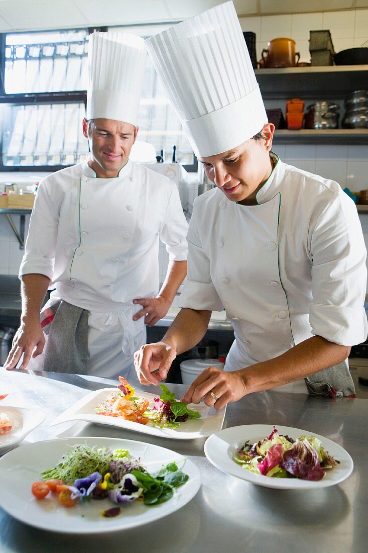 Chefs in a commercial kitchen preparing a salad