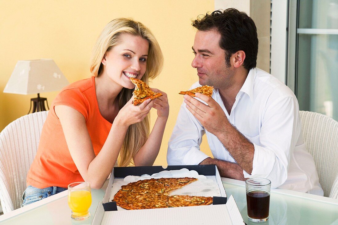 Mann und Frau essen Pizza aus Pizzakarton