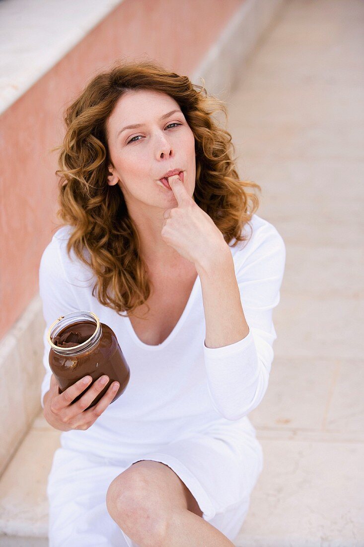 Frau beim Naschen von Nussnougatcreme aus einem Glas