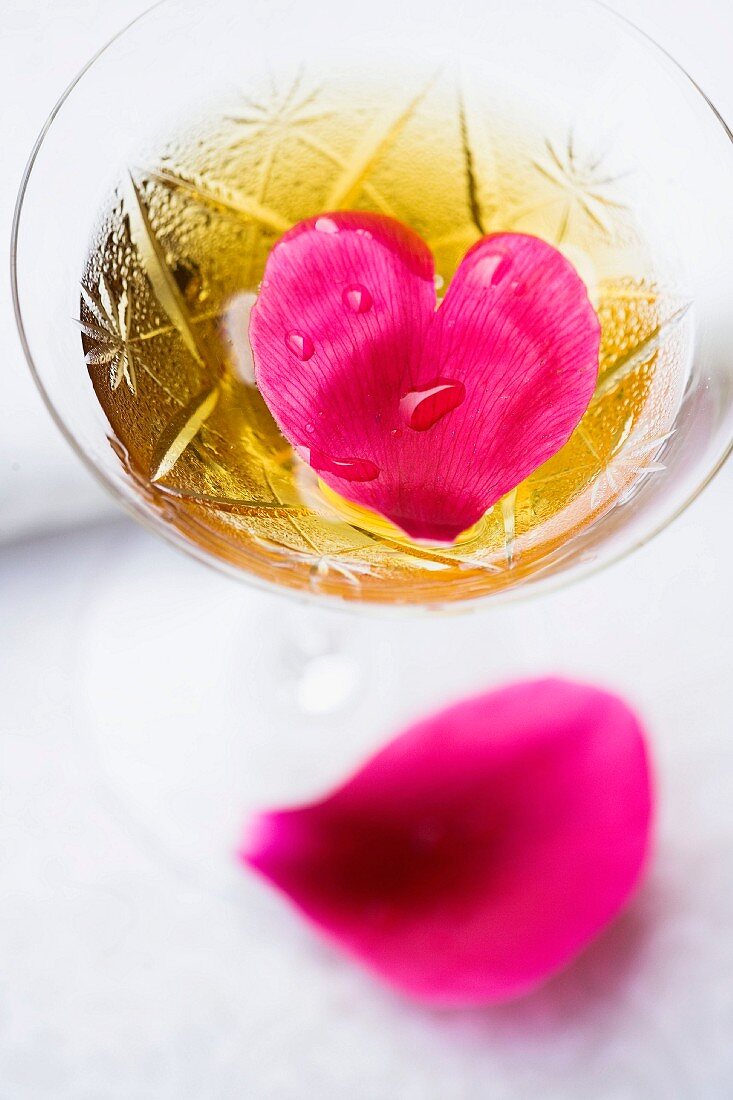 Heart-shaped petal in glass of sparkling wine
