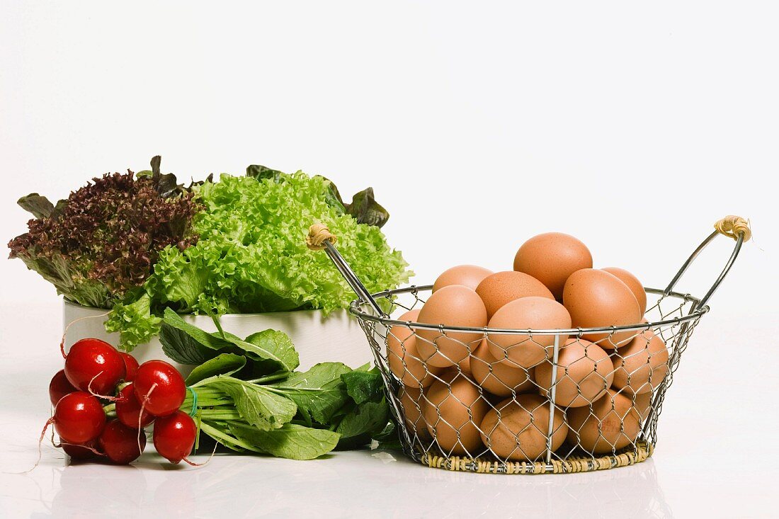 Eggs in a wire basket and a bowl of lettuce
