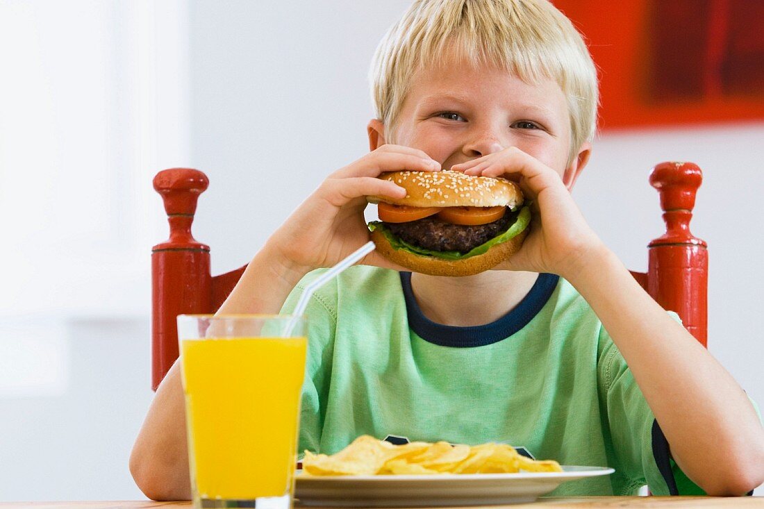 Junge mit einem Hamburger und einem Glas Limonade