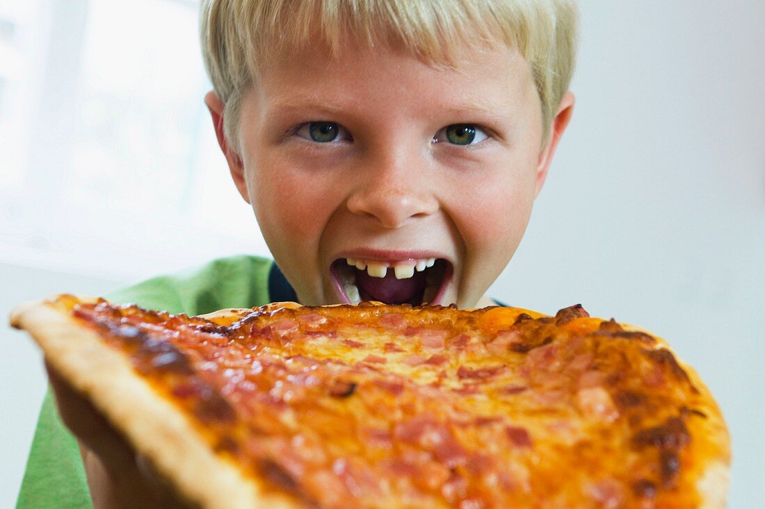 Junge beisst in eine Pizza