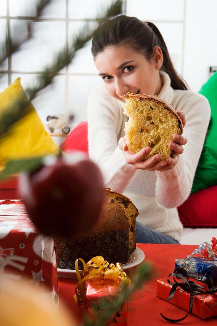 Frau an Weihnachten hält ein Stück Panettone