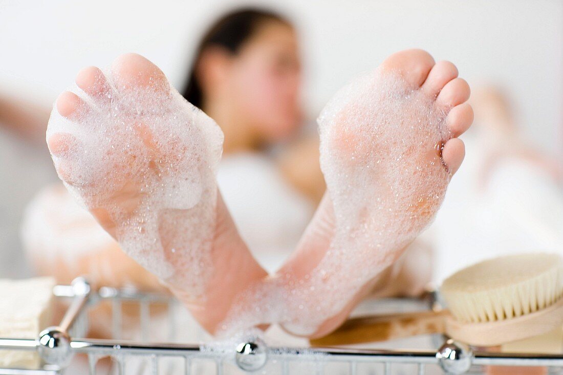 Feet of woman lying in bathtub