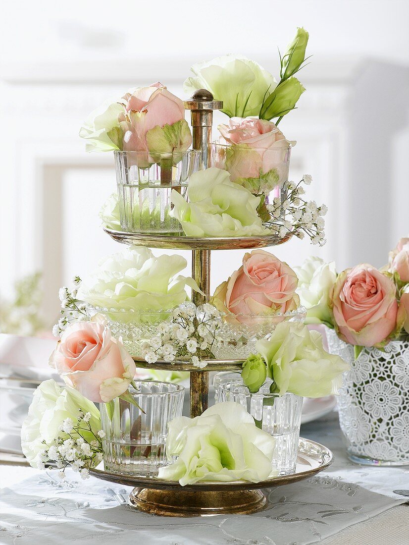 Roses and lisianthus flowers in glasses on tiered stand