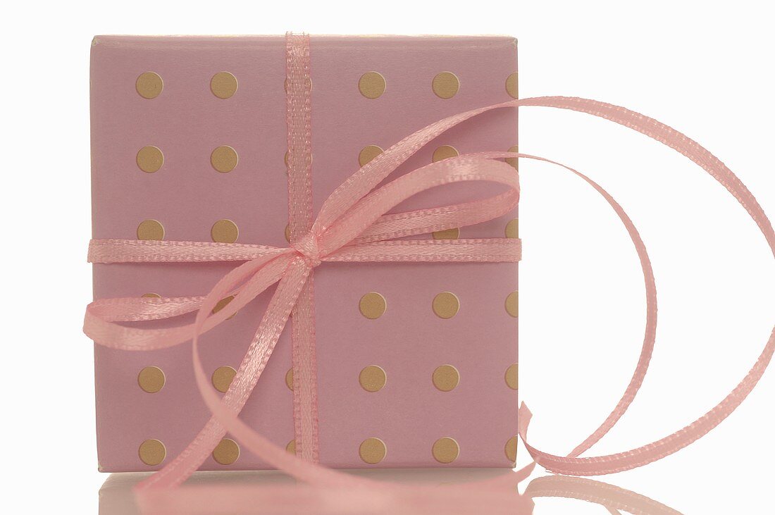 Gift in spotted gift wrapping paper with pink ribbon