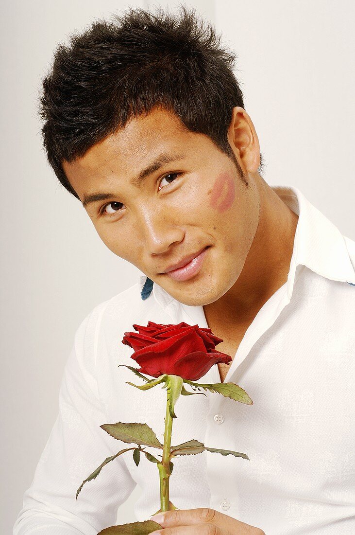 Asiatischer Mann mit roter Rose und Lippenstiftabdruck
