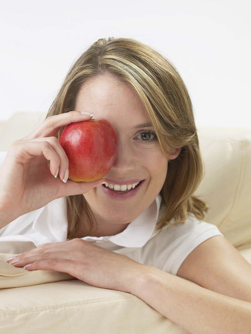 Woman holding an apple in front of her eye