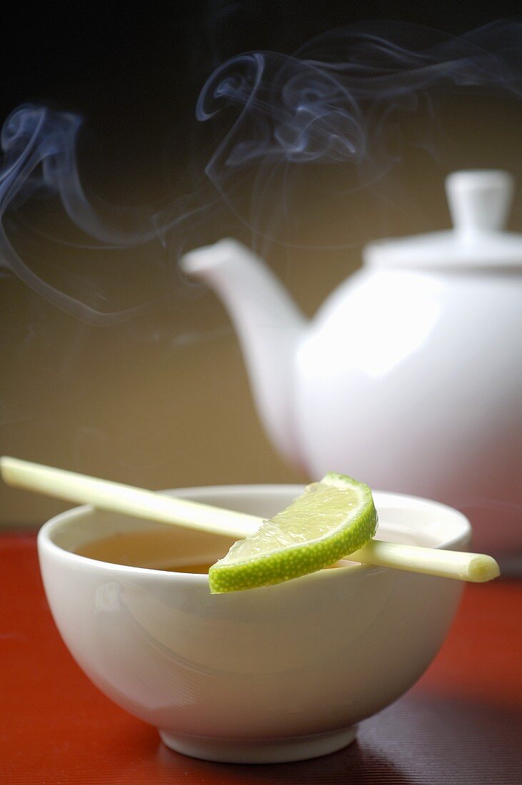 Teapot and bowl of tea with a slice of lime