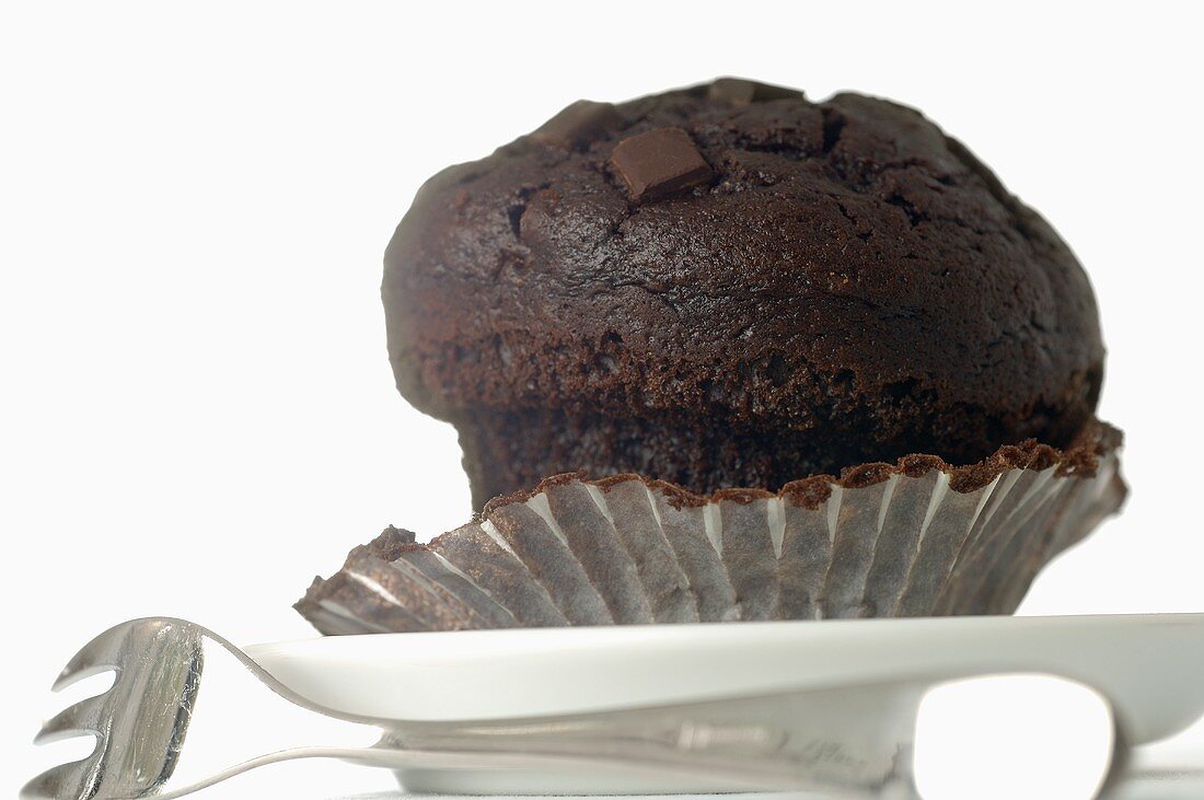 Chocolate muffin in paper case, fork beside it