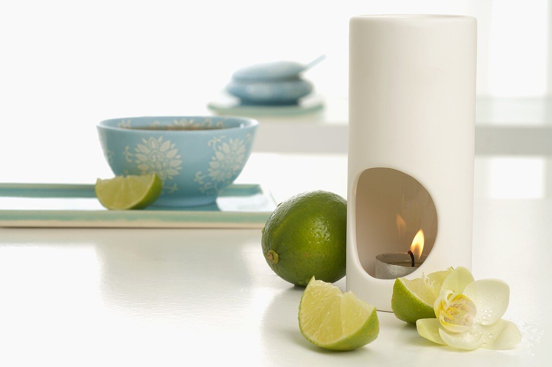 Duftlampe mit Limetten und Orchideenblüte, Teeschale