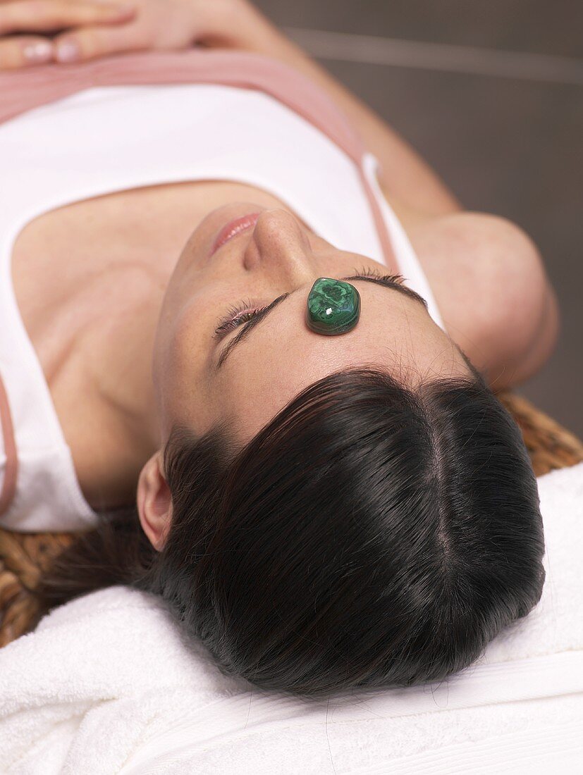 Woman lying down with a healing stone on her forehead