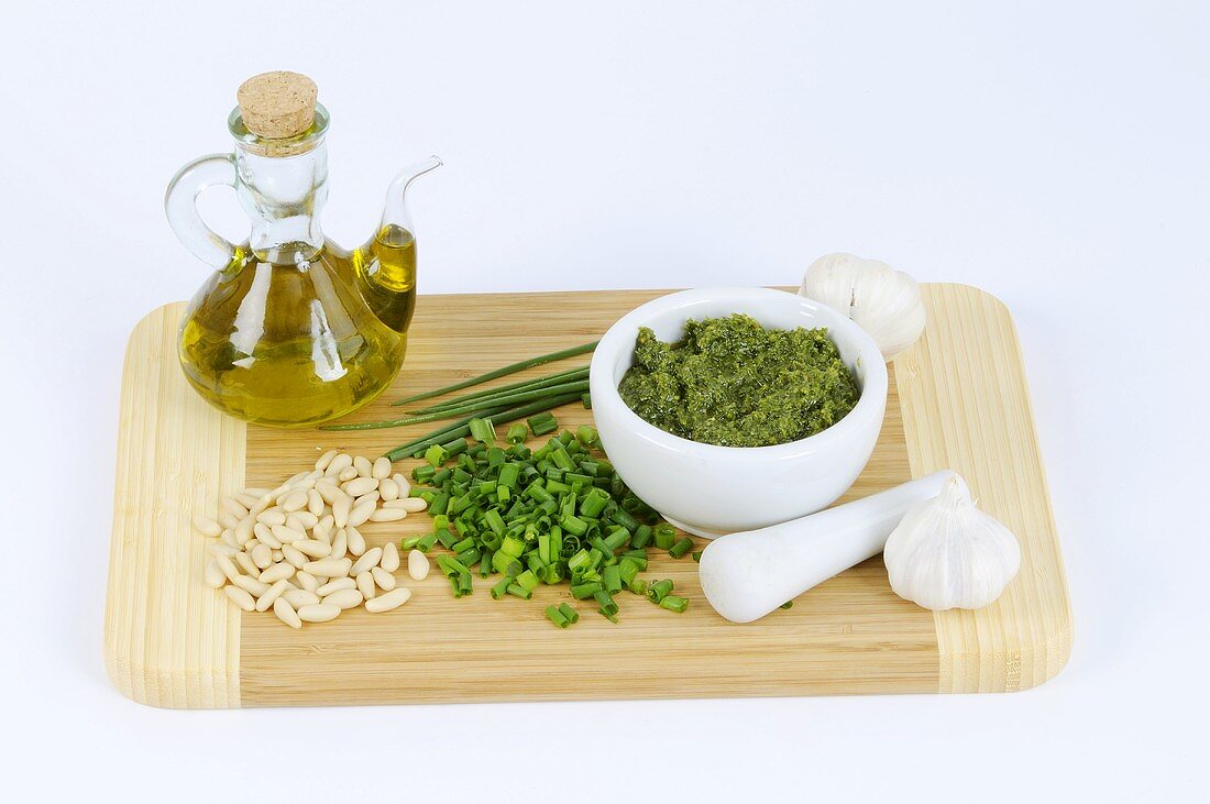 Chive pesto surrounded by ingredients on chopping board