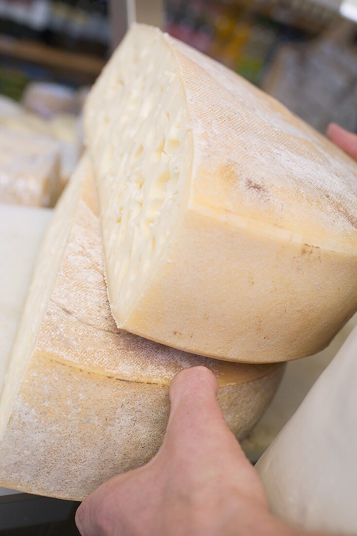 Hands holding two large pieces of Bergkäse (Alpine) cheese