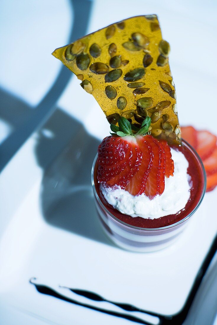 Layered strawberry and cream dessert with pumpkin seed wafer