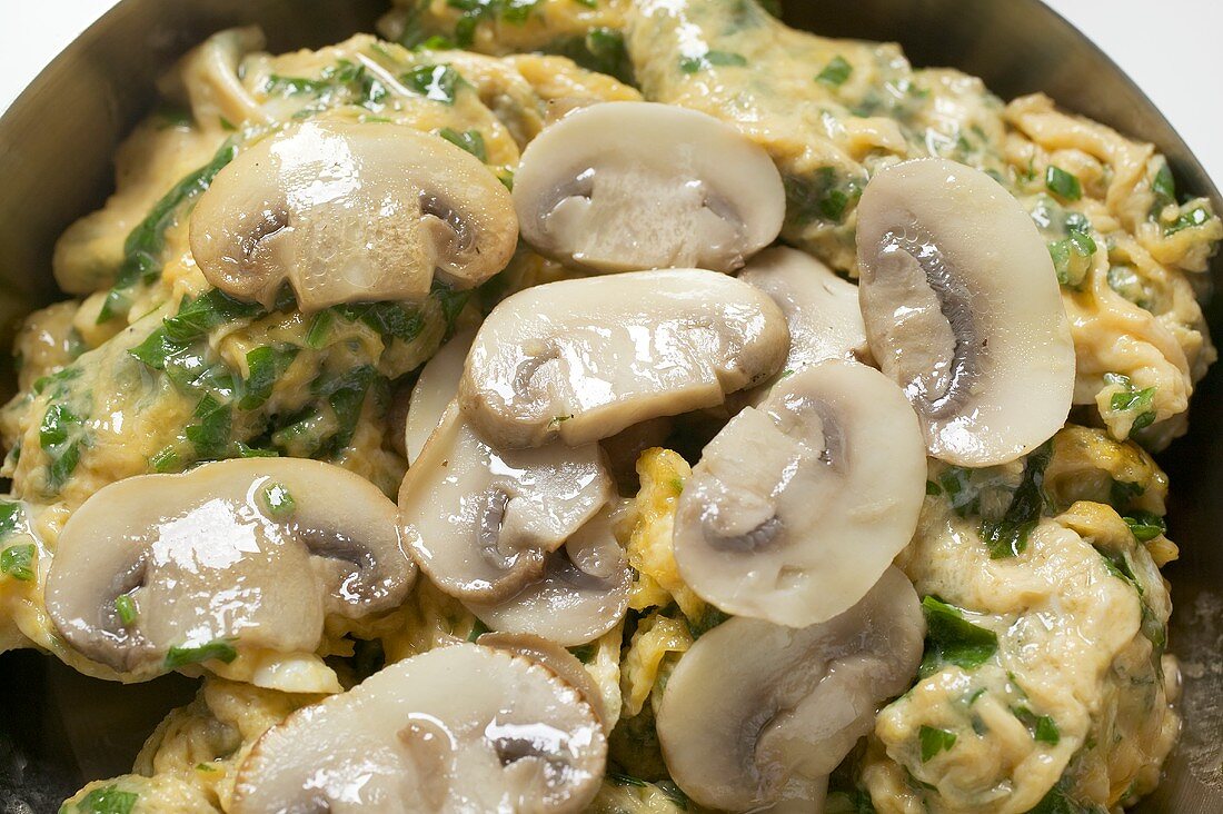 Omelette with mushrooms in frying pan (close-up)