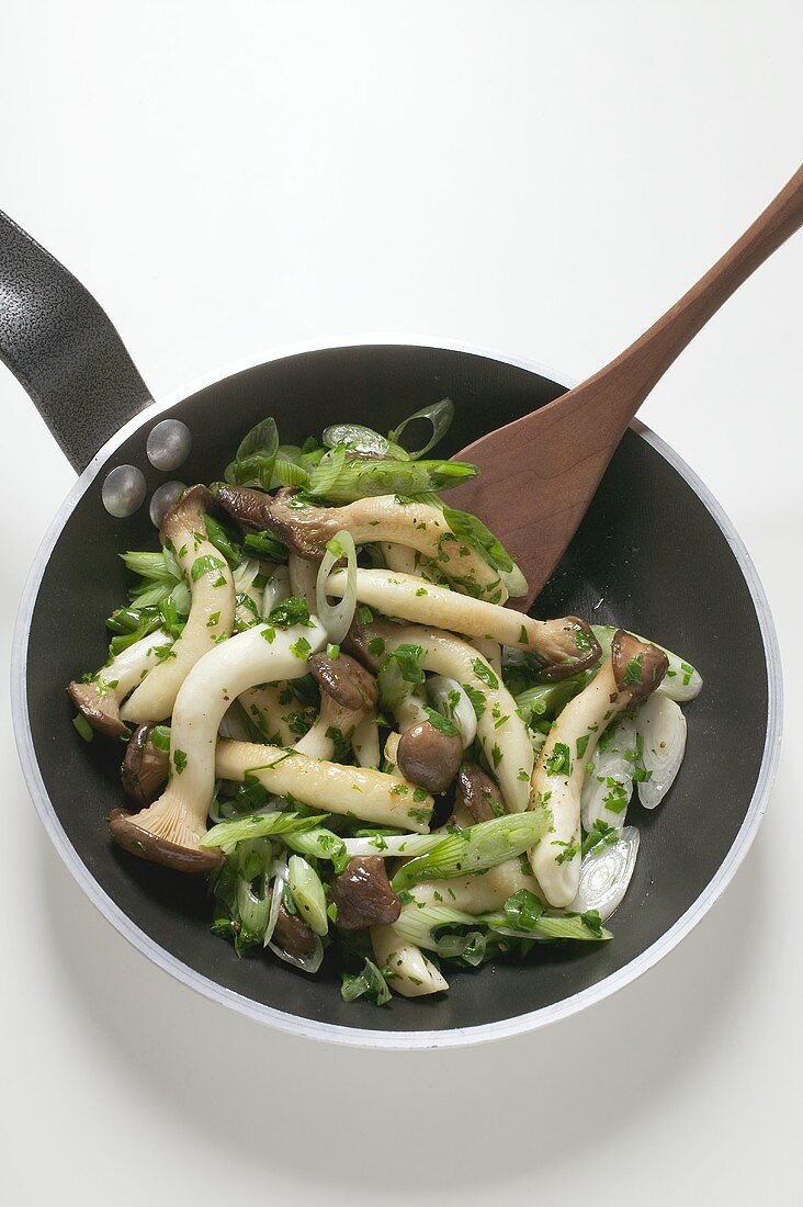 Fried king oyster mushrooms and spring onions in frying pan