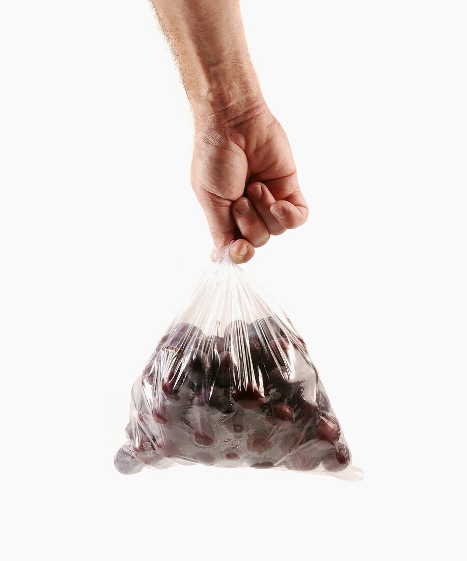 Hand holding a bag of plums
