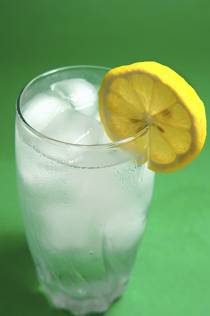 A glass of mineral water with ice cubes and slice of lemon