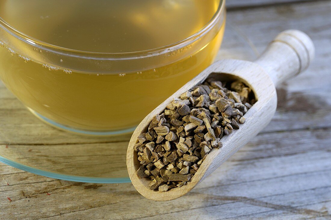 Tree peony root bark in wooden scoop and cup of tea