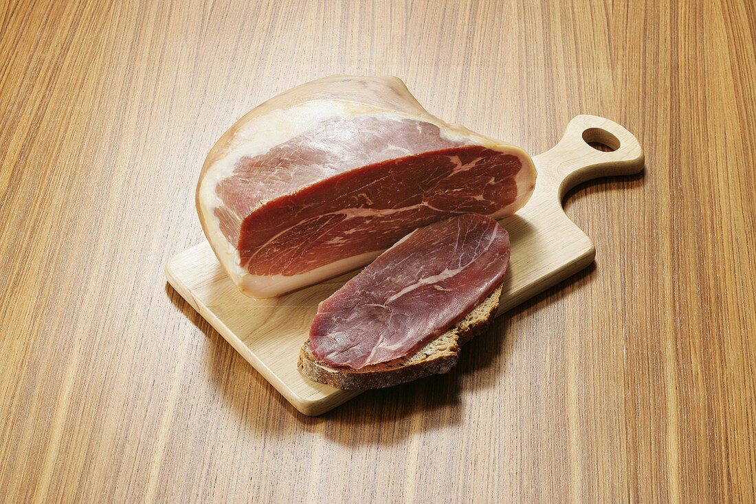 A piece of air-dried ham with slice of ham on bread