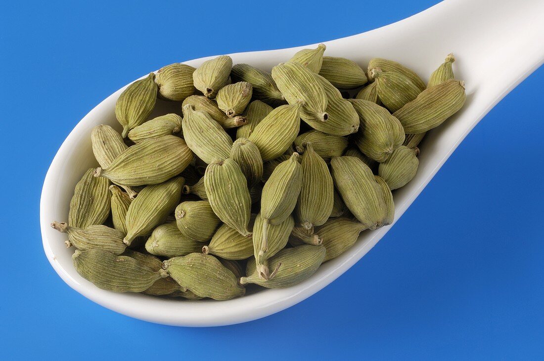 Cardamom pods on a porcelain spoon