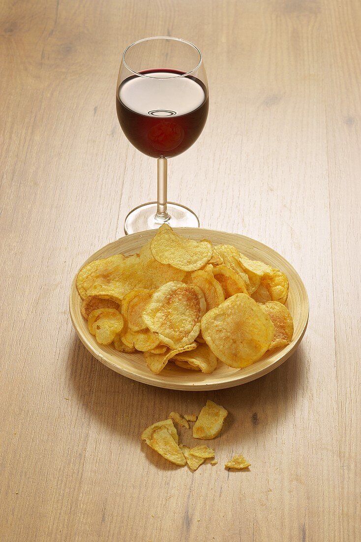 Schälchen mit Chips und ein Glas Rotwein