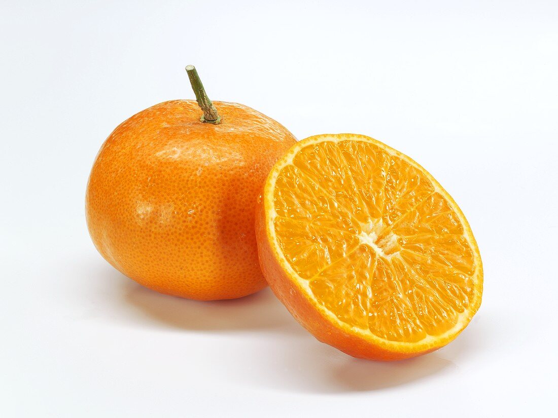 Mandarin orange half in front of whole mandarin orange