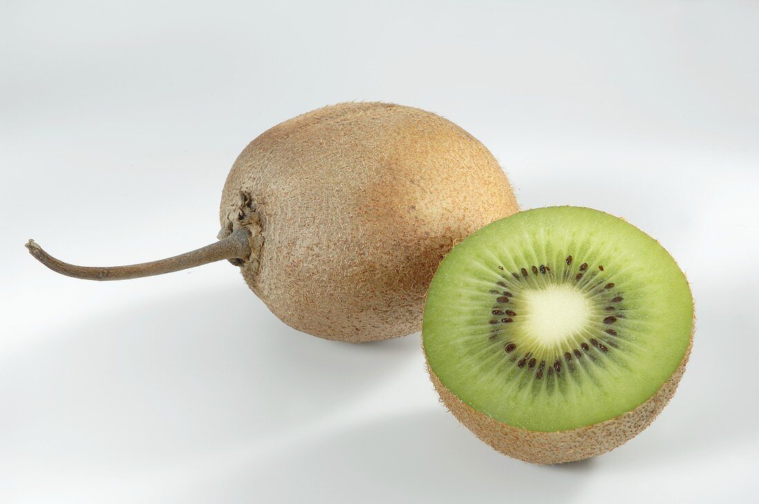 Kiwi fruit half in front of whole kiwi fruit