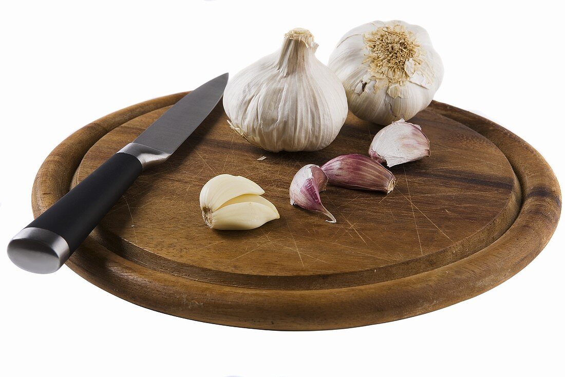 Garlic cloves and garlic bulbs with knife on wooden board