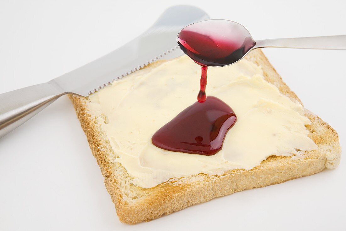 Spreading jam on buttered toast