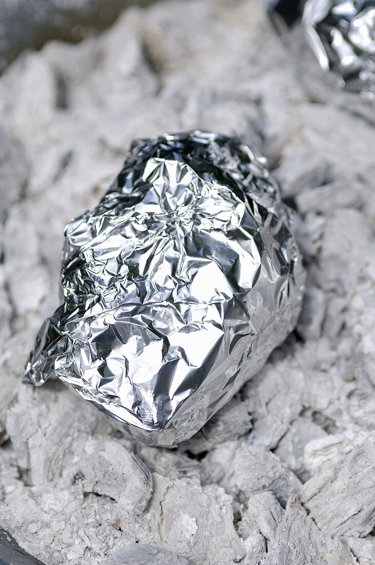 Potato baked in foil in the embers of a fire