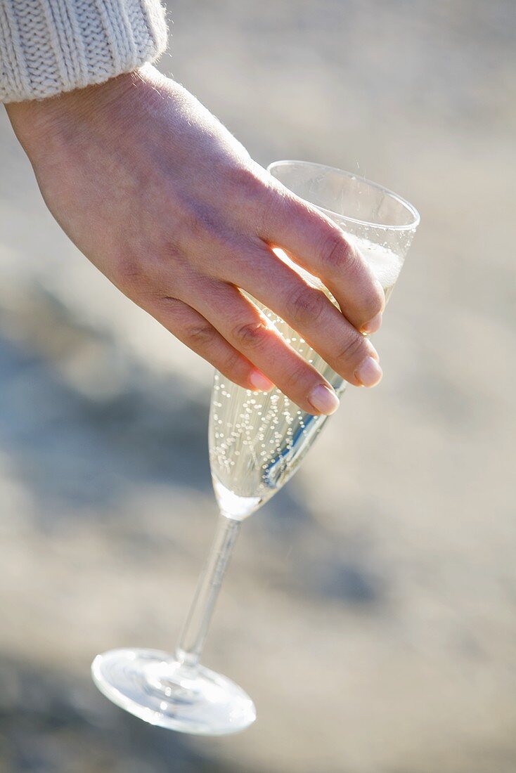 Hand hält ein Glas Champagner