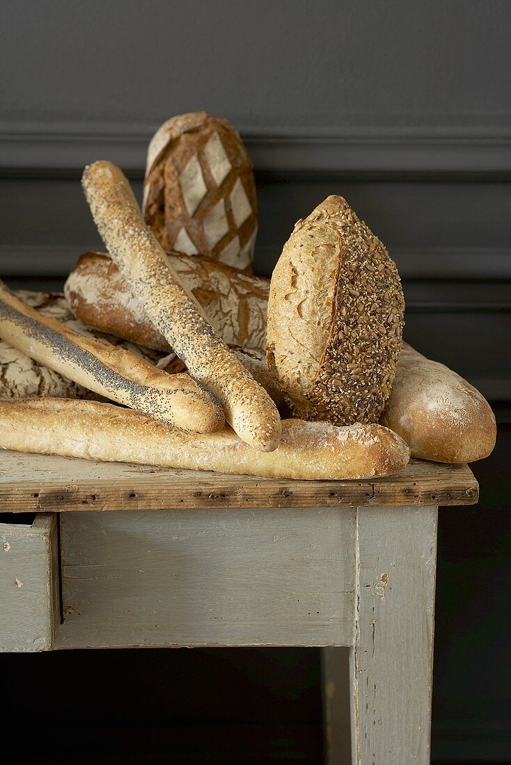 Verschiedene rustikale Brote, Baguettes auf einem Holztisch