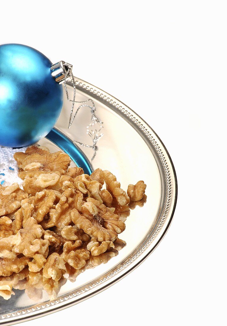 Shelled walnuts in a dish with a blue Christmas bauble