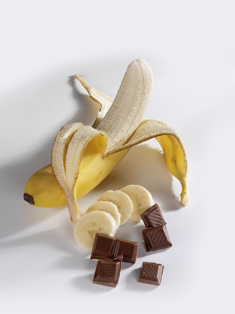 A partly-peeled banana and pieces of chocolate