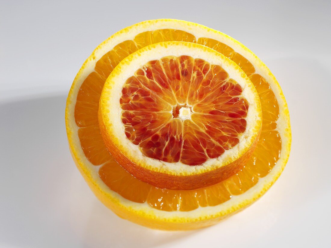 Eine Blutorangenscheibe auf einer Orangenhälfte