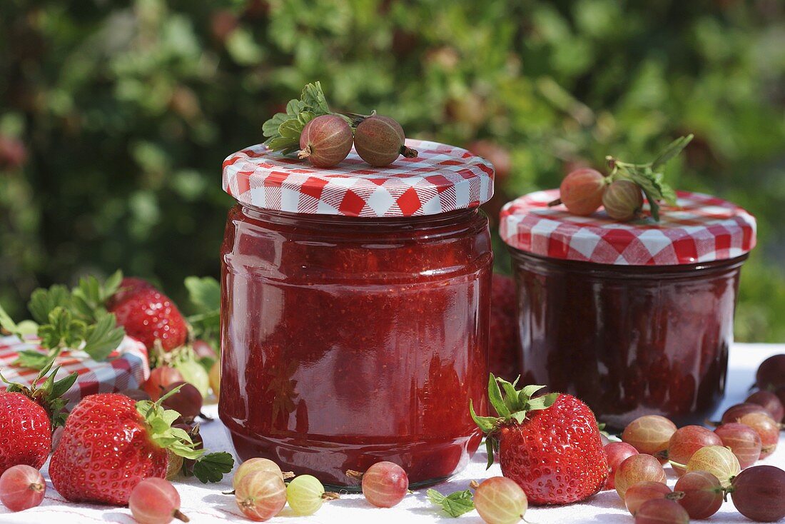 Two jars of strawberry and gooseberry jam and fruit