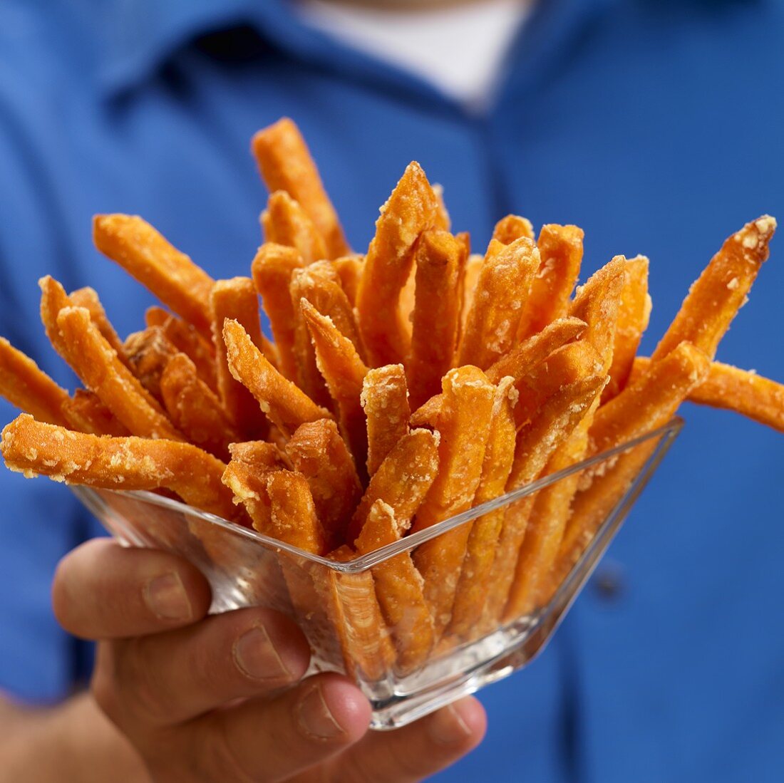 Mann hält Glasschale mit frittierten Süsskartoffelstäbchen