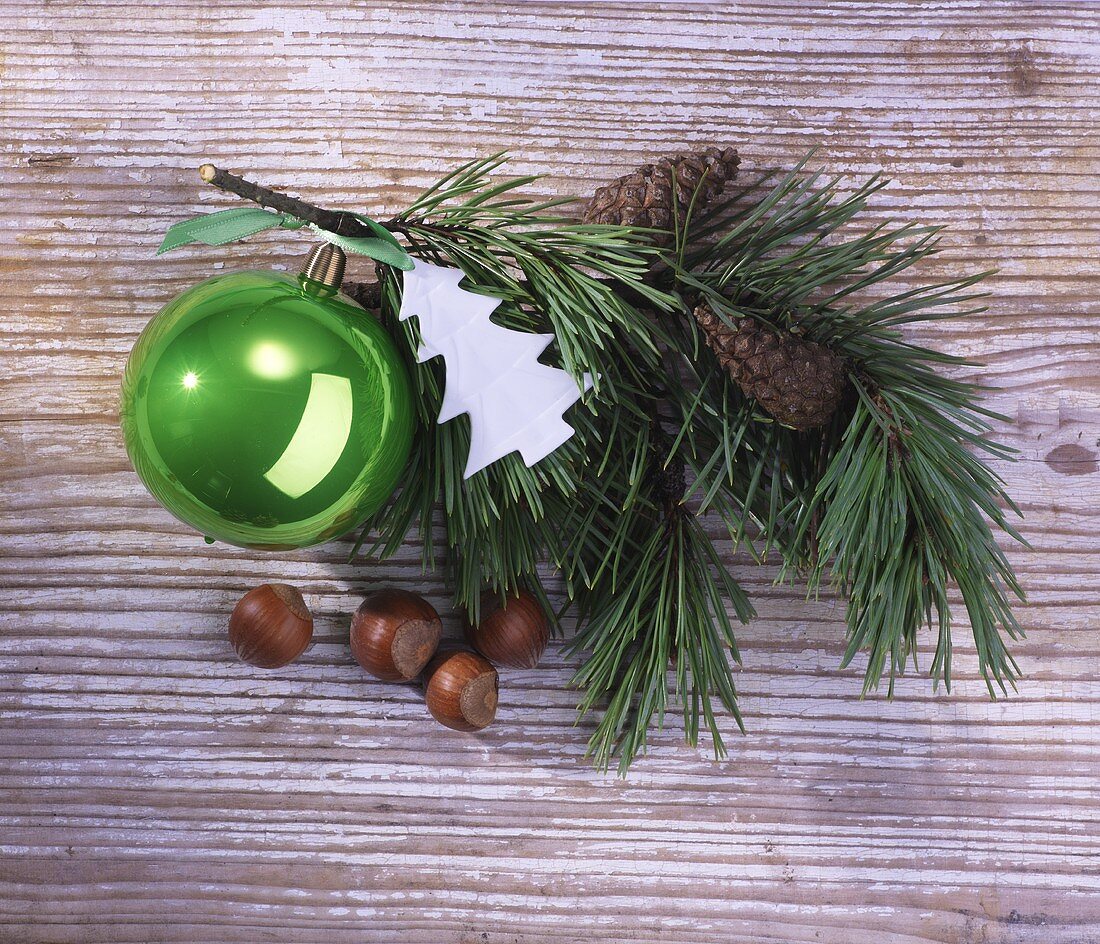 A sprig of pine with Christmas decoration on a wooden surface