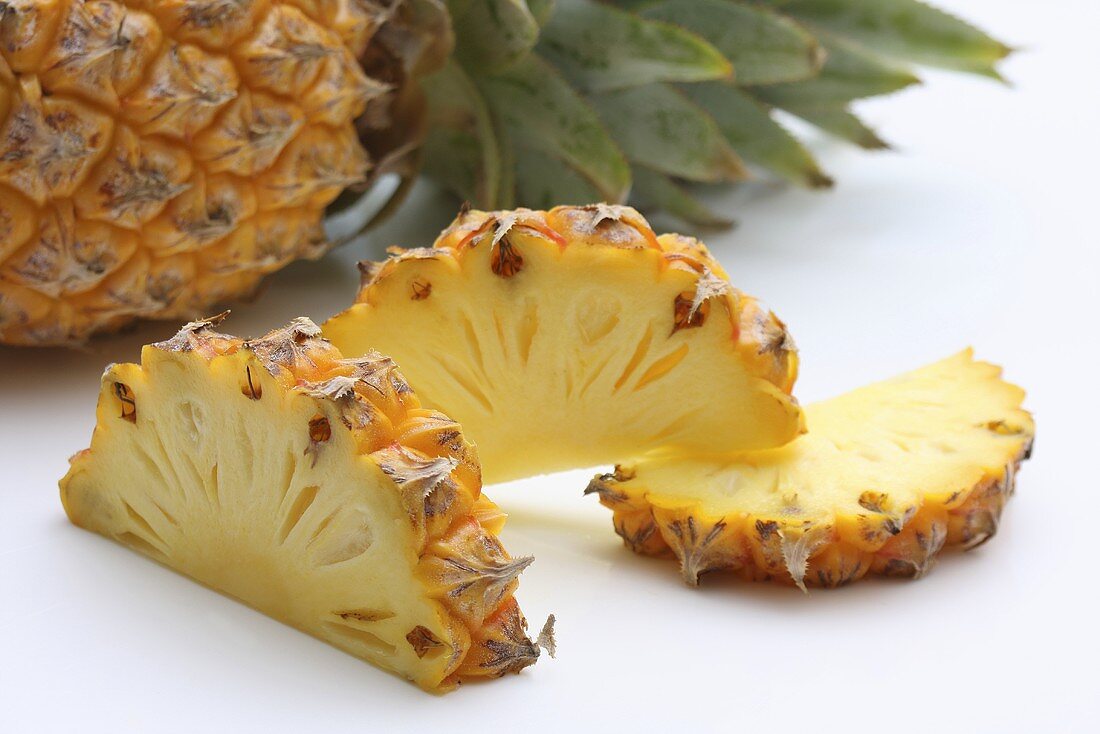 Pineapple slices in front of a whole pineapple