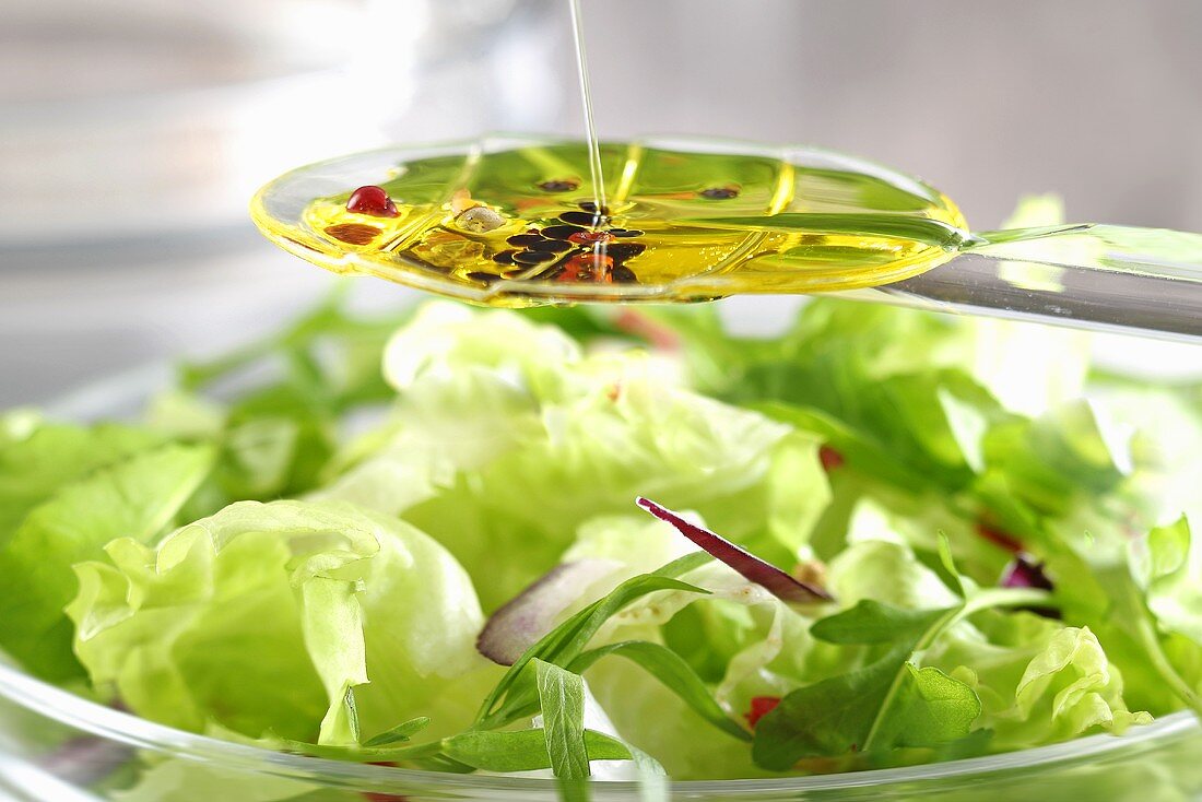 Vinaigrette on a spoon above a bowl of salad