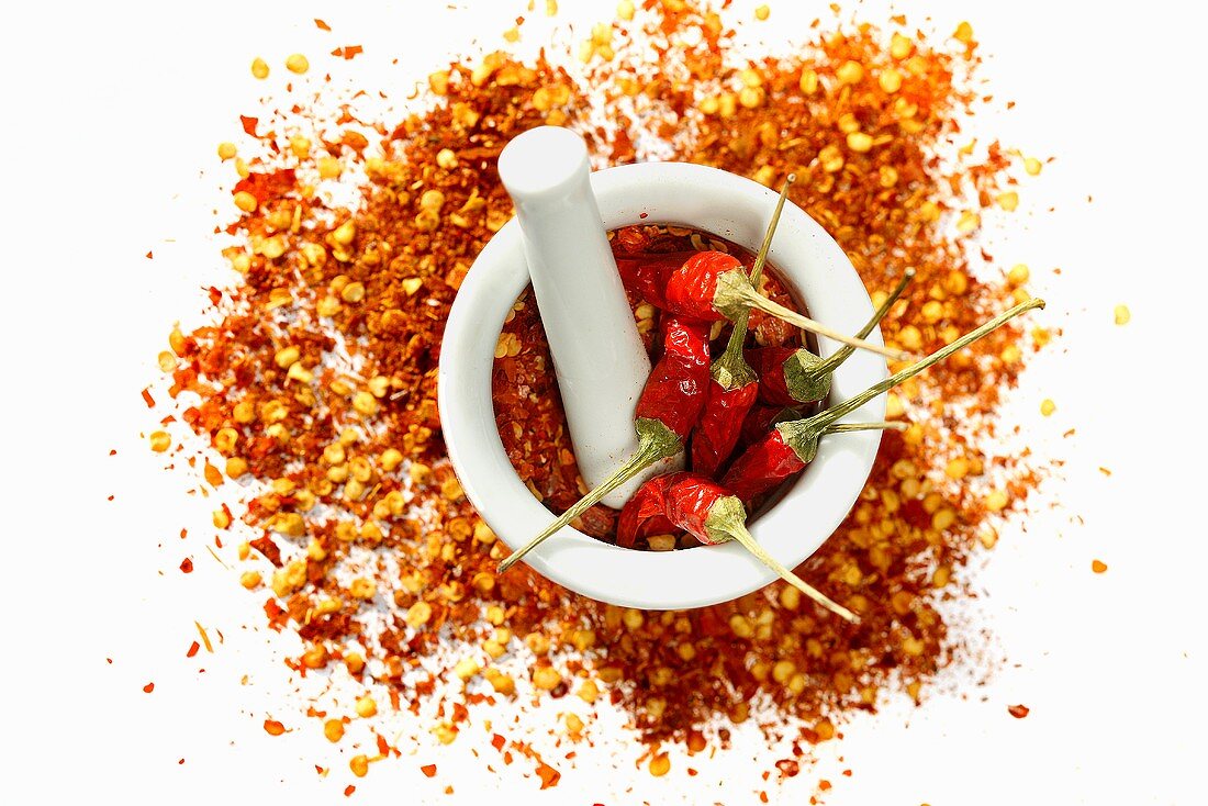 Dried chilli peppers and chilli flakes in a mortar