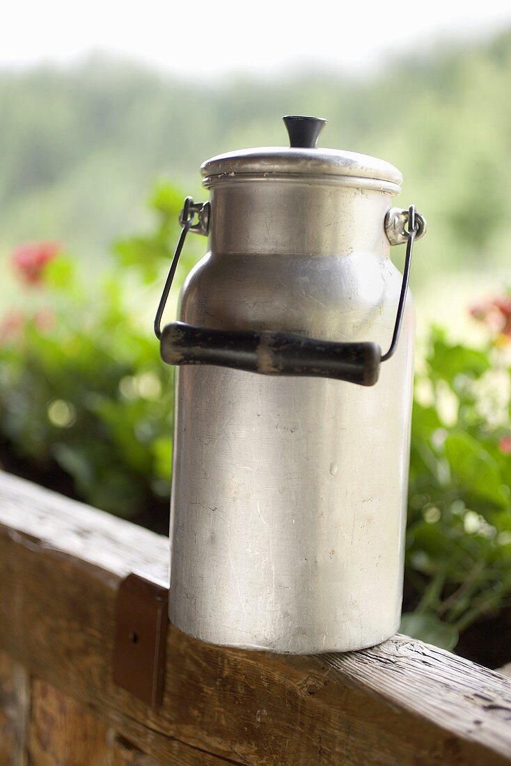 Milk can on a wooden railing